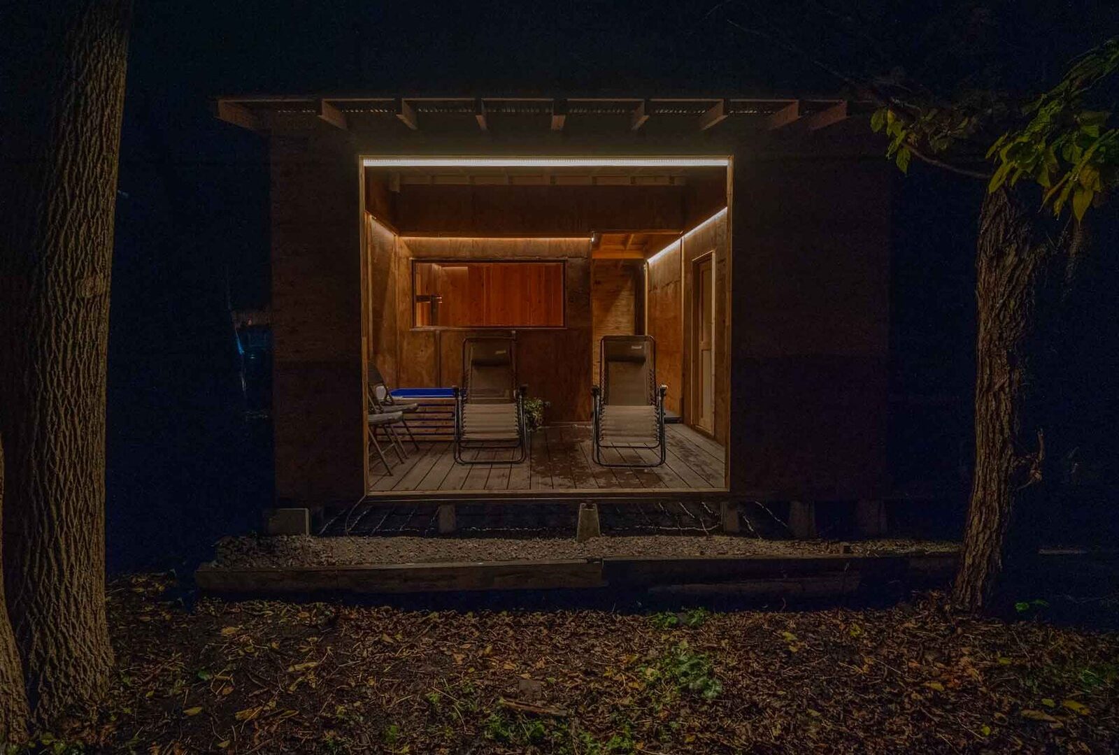 夜に暖色で灯るサウナ小屋と外気浴スペース、小樽・朝里川温泉 旅房はなえみ